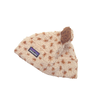 A beige Patagonia fleece beanie with brown spots and a brown pom-pom on top, shown on a plain white background.