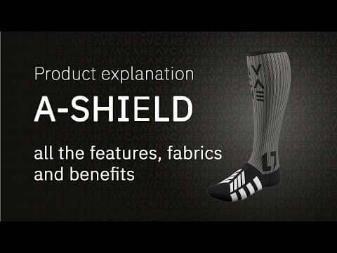 Product explanation graphic for the A-Shield sock, showing a single ribbed knee-high sock with black and white stripes and branding on a dark textured background with text reading 'Product explanation A-SHIELD all the features, fabrics and benefits'.